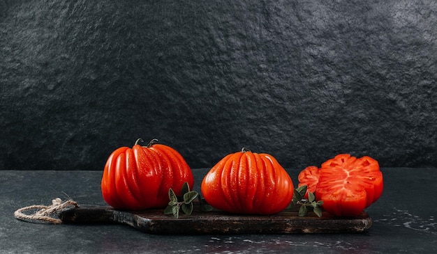 Tomates de boeuf Raf Coeur De Boeuf fraîches entières et tranchées avec origan sur fond gris concept de restaurant