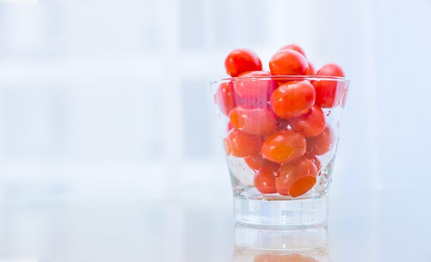 Tomates à la cerise dans une tasse en verre sur fond blanc