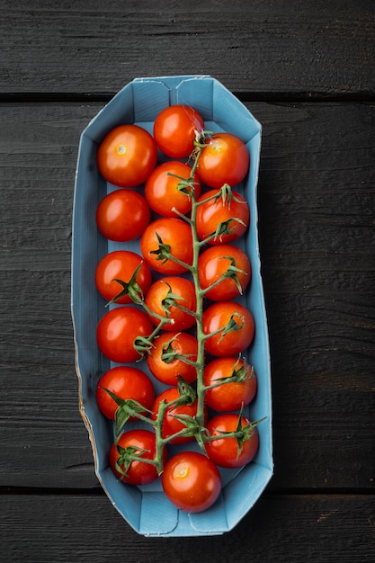 Tomates cerises biologiques rouges fraîches, sur table en bois noir