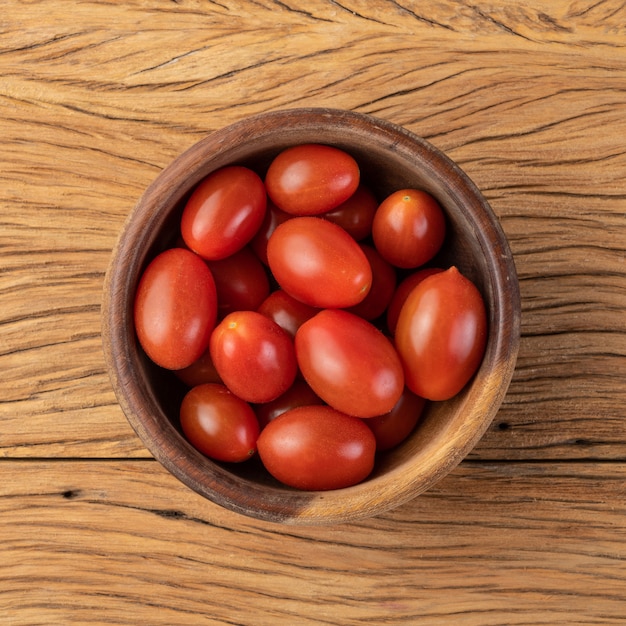 Tomates cerises sur un bol au-dessus d'une table en bois.