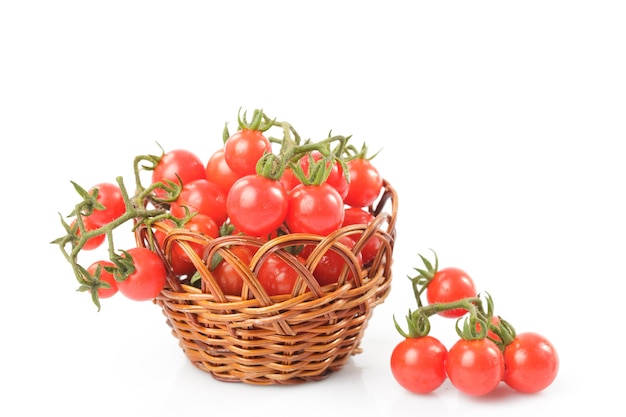 Tomates cerises sur des brindilles dans un panier isolé sur fond blanc