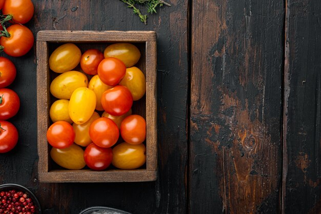 Tomates cerises de couleur mixte dans un plateau en bois, sur la vieille table en bois, vue du dessus