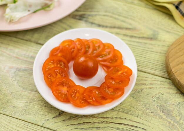 Tomates cerises dans une assiette blanche sur un fond en bois