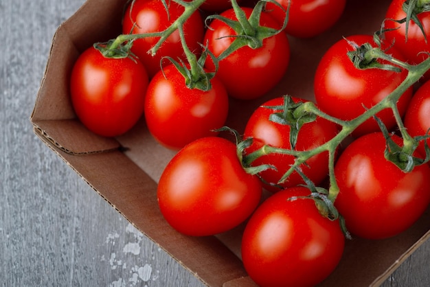 Tomates cerises dans une boîte en carton sur un fond en bois Tomates fraîches avec espace de copie