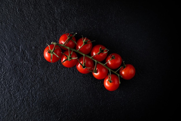 Tomates cerises flatlay sur une branche sur un fond sombre