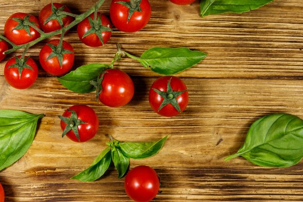 Tomates cerises fraîches avec des feuilles de basilic vert sur une table en bois Vue de dessus