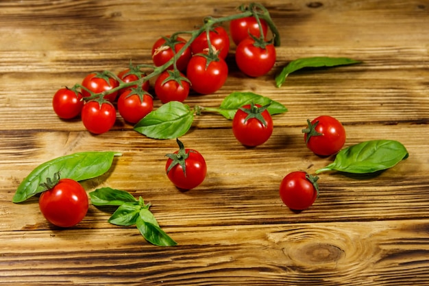 Tomates cerises fraîches avec des feuilles de basilic vert sur une table en bois