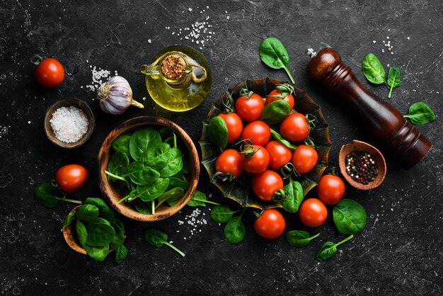 Tomates cerises fraîches et feuilles d'épinards vertes Vue de dessus Sur un fond de pierre