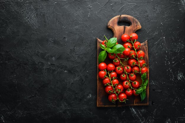 Tomates cerises fraîches sur fond noir. Vue de dessus. Espace libre pour votre texte.