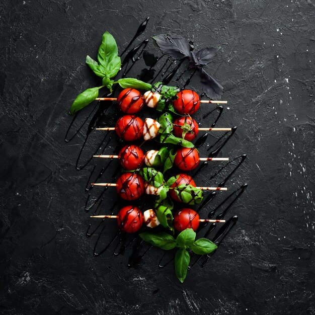 Tomates cerises, mozzarella et basilic. Sur un fond de pierre noire. Cuisine italienne. Vue de dessus. Espace libre pour votre texte.
