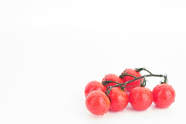 Tomates cerises mûres sur une brindille sur fond blanc - image