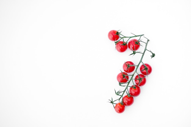 Tomates cerises mûres rouges sur une surface blanche