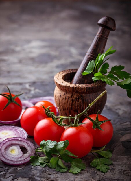 Tomates cerises, oignons rouges et mortier pour les épices. Mise au point sélective