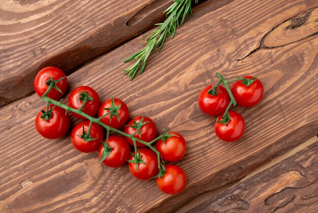 Tomates cerises et romarin sur fond de bois Branche de tomates fraîches Nourriture végétarienne