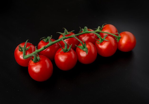 Tomates cerises et romarin sur fond noir Branche de tomates fraîches Nourriture végétarienne