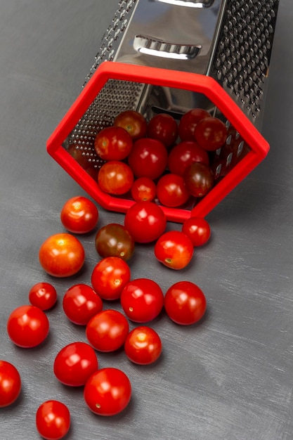 Les tomates cerises rouges débordent d'une râpe rouge