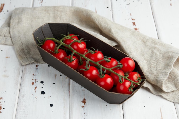 Tomates cerises rouges fraîches sur fond de bois blanc