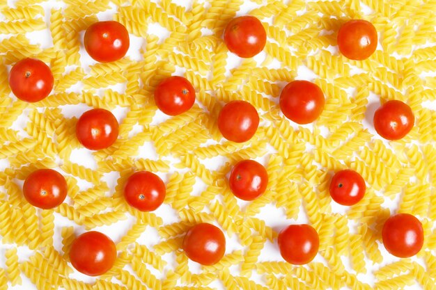 Tomates cerises rouges et pâtes fusilli crues sur fond blanc