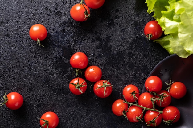 Des tomates cerises sont tombées de l'assiette. fond sombre décoré de feuilles de salade