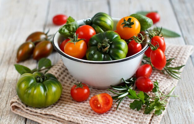 Tomates colorées dans un bol sur une table en bois se bouchent