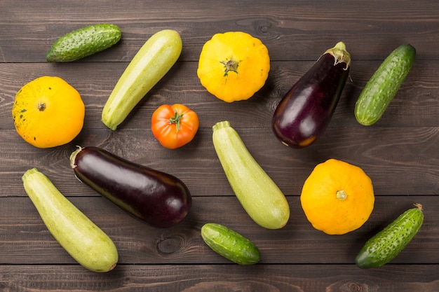 Tomates, concombres, citrouilles de brousse, aubergines et courgettes sur une table en bois sombre.