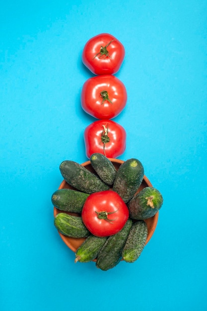 Tomates et concombres mûrs sur fond bleu