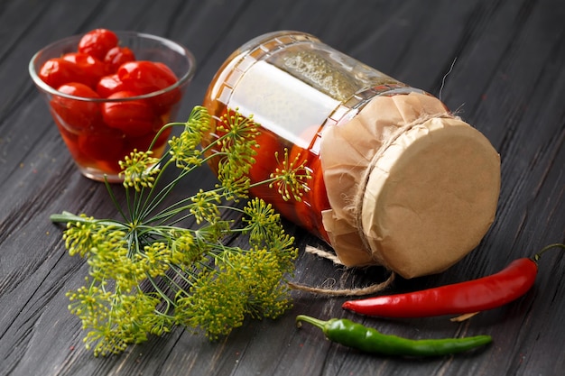 Tomates en conserve marinées sur une assiette et dans un bocal tomates rouges et épices sur fond noir