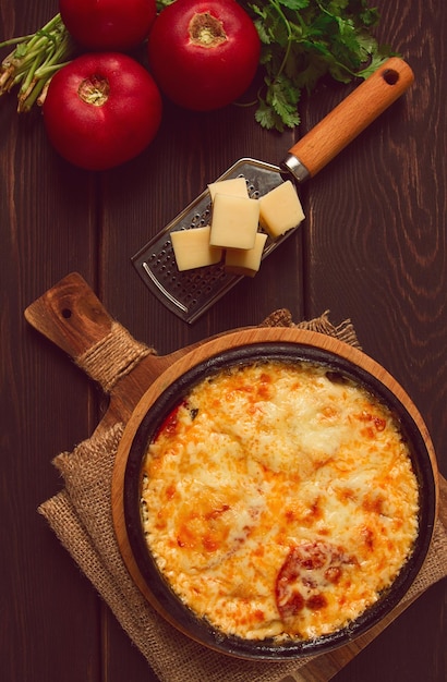 Photo tomates cuites au four avec du fromage suluguni ketsi dans une poêle en argile plat géorgien fait maison vue de dessus sur une table en bois aucun peuple