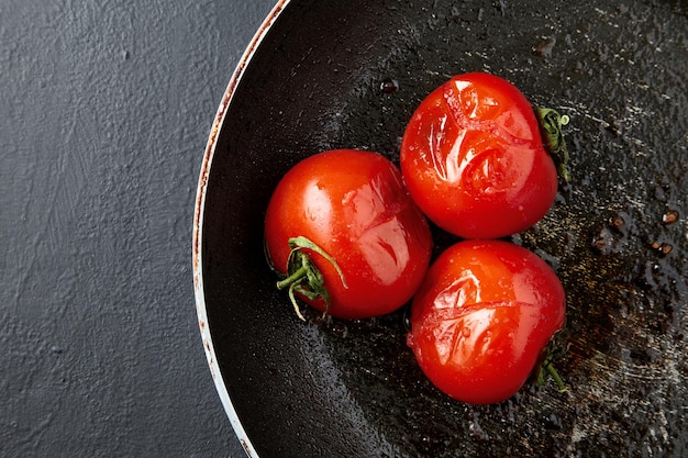 Tomates cuites grillées frites dans une poêle noire sur une table en béton noir
