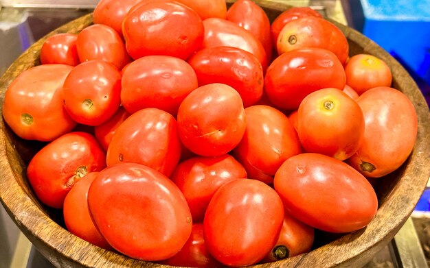 Des tomates dans un bol en bois sur le comptoir du marché