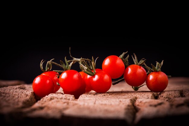 Tomates dans une plaque en bois sur fond noir