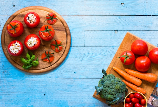 Tomates farcies au fromage et aux différents légumes, sur une table en bois,