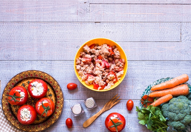 Tomates farcies au fromage et différents légumes sur bois