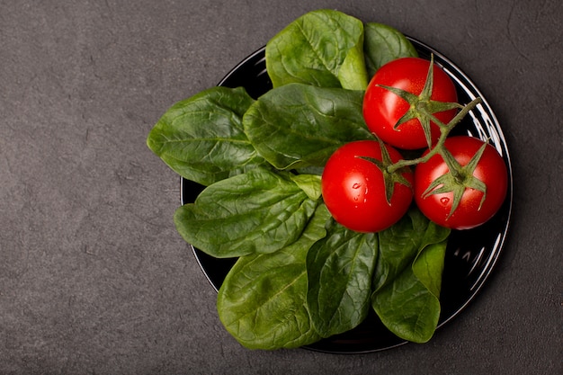 Tomates et feuilles d'épinards sur plaque noire