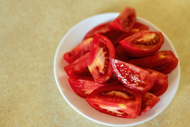 Tomates fraîchement coupées sur une plaque blanche. Assiette blanche avec des tranches de tomates sur une table. Beaucoup d'espace de copie.