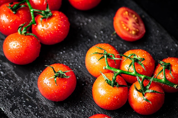 Tomates fraîches sur une branche sur une planche en pierre