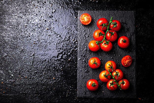 Tomates fraîches sur une branche sur une planche en pierre