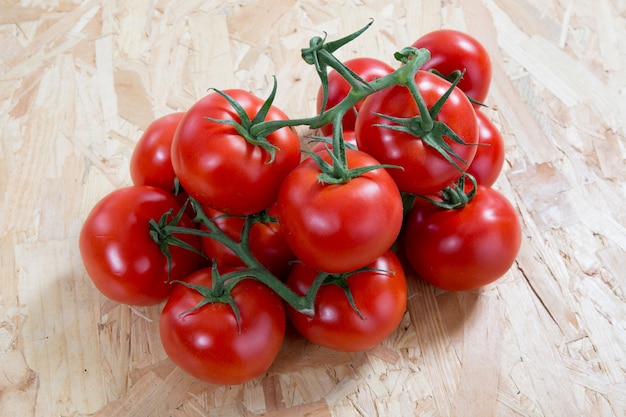 Tomates fraîches sur un cluster sur une table en bois