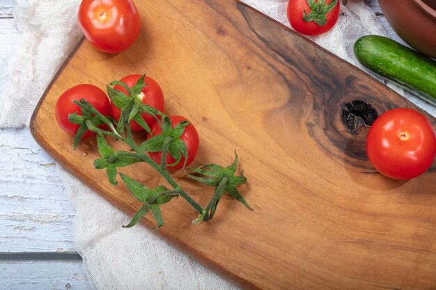 Tomates fraîches dans une assiette en bois sur blanc