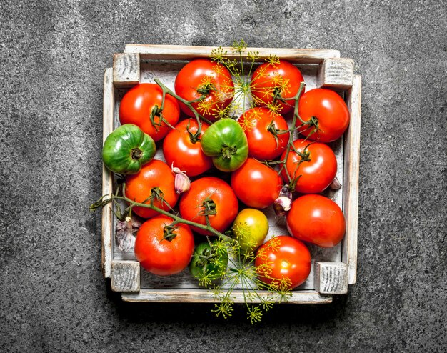 Tomates fraîches dans une boîte sur une planche de pierre