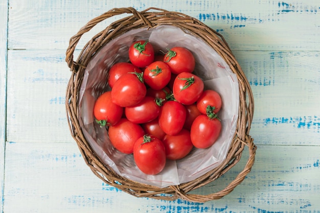 Tomates fraîches dans un panier sur un fond en bois