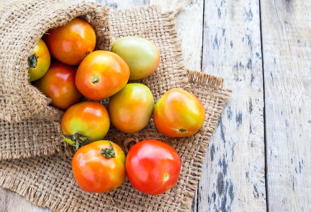 Tomates fraîches dans un sac de jute sur une table en bois