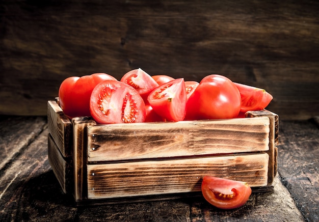 Tomates fraîches dans une vieille boîte. Sur un fond en bois.