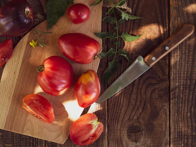 Tomates fraîches de la ferme sur une planche à découper sur une vieille table en bois