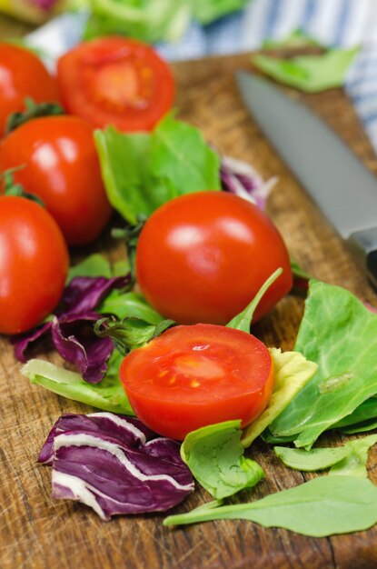 Tomates fraîches et feuilles de salade sur une planche à découper