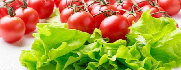 Tomates fraîches et laitue sur fond de bois blanc