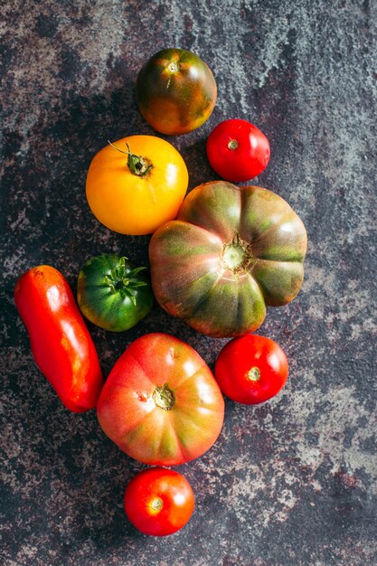Tomates fraîches et mûres multicolores sur fond sombre.
