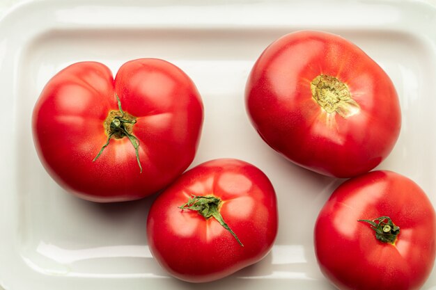 Tomates fraîches mûres sur plaque blanche, vue de dessus, gros plan