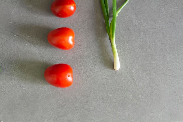 Les tomates fraîches et les oignons verts cueillis du jardin sont sur la surface de travail grise de la cuisine