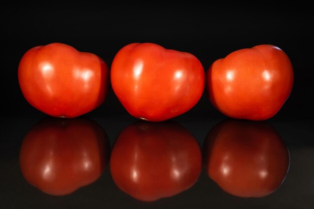 Tomates fraîches avec réflexion sur fond noir Produits biologiques